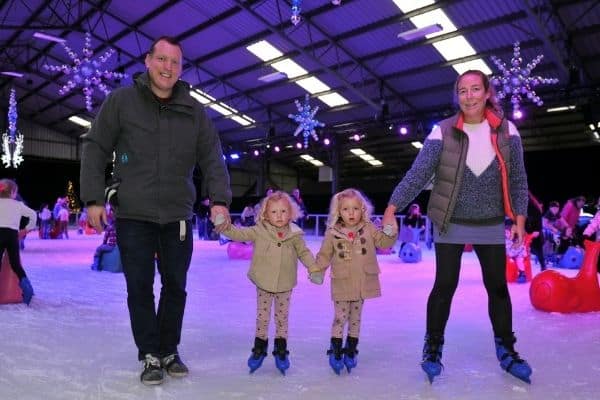 Family holding hands on the Winter Glow festive Ice Rink in Malvern, Worcestershire.