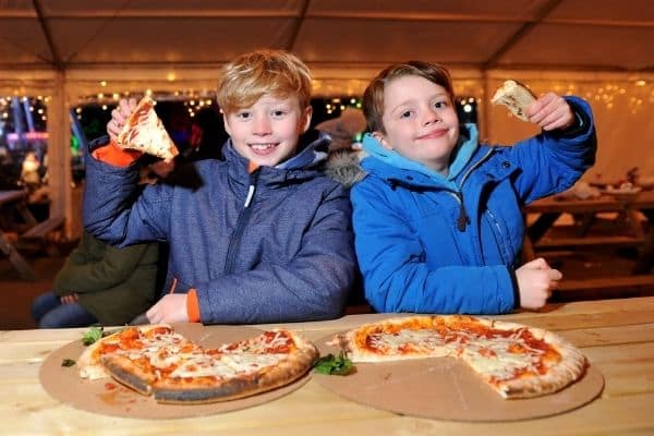 Children enjoying some yummy pizzas.