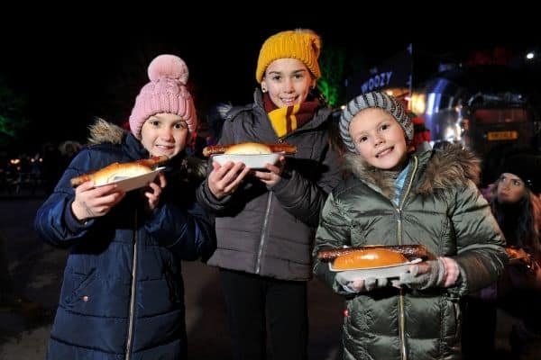 Children with jumbo hotdogs from Woozy Pig in the Winter Glow Festive Food Quarter.