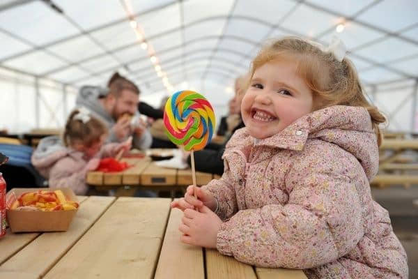 Little girl with her giant lollipop in the Festive Food Quarter at Winter Glow in Malvern, Worcestershire.