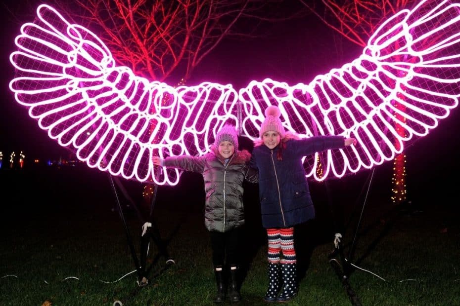 people posing in front of pink illuminated angel wings.