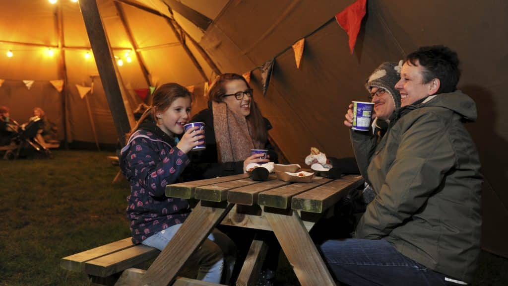 Family sat enjoying a hot drink and food at Winter Glow