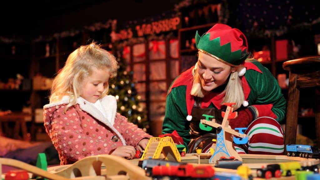 A young girl and one of Santa's elves in the Toy Workshop enjoying their Christmas experience.