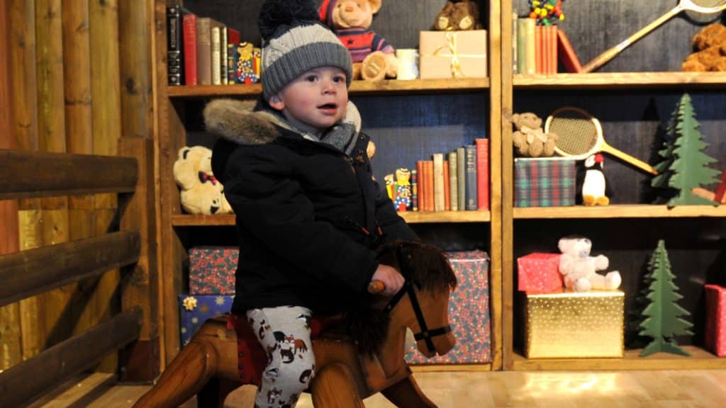 A child on a rocking chair in the Toy Workshop at Winter Glow before he sees Santa.
