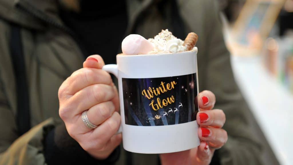 A special Winter Glow hot chocolate with whipped cream, marshmallows and chocolate biscuit stick, in a Winter Glow mug.